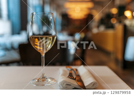 Glass of White Wine on Restaurant Table. Elegant Dining Atmosphere 129879958