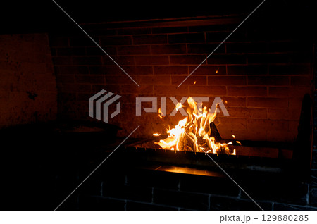 Cozy living room with a modern stone fireplace, warm flames flickering inside, creating an inviting and tranquil atmosphere. Cozy living room with a modern stone fireplace, warm flames flickering inside, creating an inviting and tranquil atmosphere. 129880285