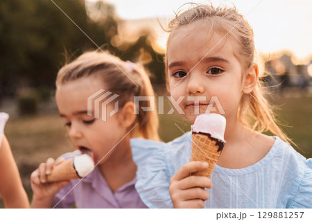 Adorable children savoring a sweet treat on a summer afternoon Adorable children savoring a sweet treat on a summer afternoon 129881257