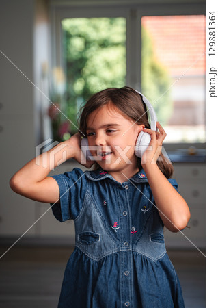 Young girl listening to music with headphones at home 129881364