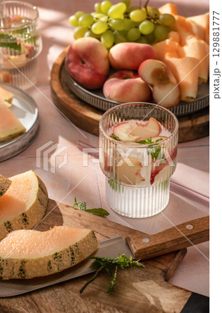 Summer cold drinks: homemade iced peach lemonade with mint in glass on pink tile background in bright morning light Summer cold drinks: homemade iced peach lemonade with mint in glass on pink tile background in bright morning light 129881777