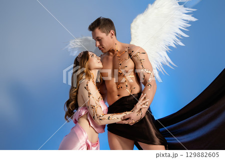 Couple in romantic embrace with angel wings and dramatic costumes 129882605