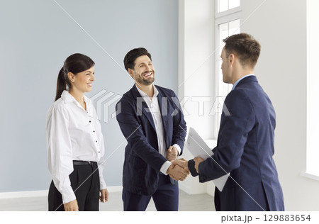 Happy couple buying new apartment, becoming homeowners, seal deal with realtor by handshake. 129883654