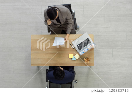 The interviewer in a suit reading candidate resume during a job interview. Top View 129883713