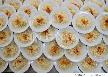 Overhead view of many plates filled with cabbage salad garnished with paprika, catering and food service concept 129883785