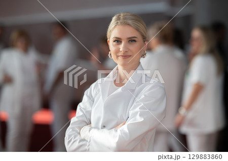 Young female doctor posing in front of medical staff Young female doctor posing in front of medical staff 129883860