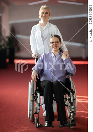 Nurse helping happy elderly woman in wheelchair 129883865