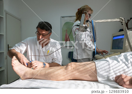 Doctors performing patient diagnostics with equipment Doctors performing patient diagnostics with equipment 129883910