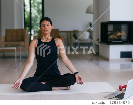 Young Beautiful Female Exercising, Stretching and Practising Yoga with Trainer via Video Call Conference in Bright Sunny House. Healthy Lifestyle, Wellbeing and Mindfulness Concept. Young Beautiful Female Exercising, Stretching and Practising Yoga with Trainer via Video Call Conference in Bright Sunny House. Healthy Lifestyle, Wellbeing and Mindfulness Concept. 129884070