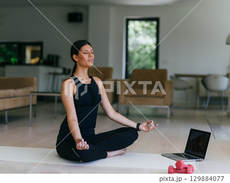 Young Beautiful Female Exercising, Stretching and Practising Yoga with Trainer via Video Call Conference in Bright Sunny House. Healthy Lifestyle, Wellbeing and Mindfulness Concept. 129884077
