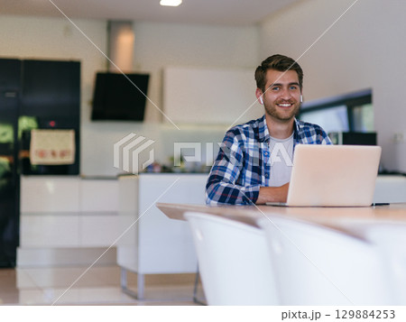 Man Smiling While Working on Laptop 129884253