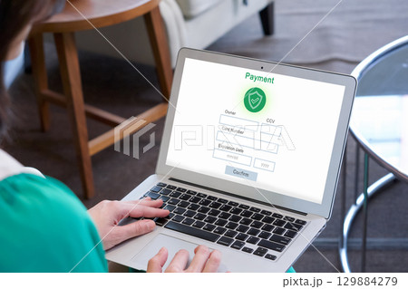 A lady is busy typing on her laptop computer which show a payment form on its screen. 129884279