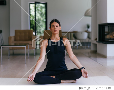 Young Beautiful Female Exercising, Stretching and Practising Yoga with Trainer via Video Call Conference in Bright Sunny House. Healthy Lifestyle, Wellbeing and Mindfulness Concept. Young Beautiful Female Exercising, Stretching and Practising Yoga with Trainer via Video Call Conference in Bright Sunny House. Healthy Lifestyle, Wellbeing and Mindfulness Concept. 129884436