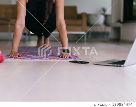 Young Beautiful Female Exercising, Stretching and Practising Yoga with Trainer via Video Call Conference in Bright Sunny House. Healthy Lifestyle, Wellbeing and Mindfulness Concept. Young Beautiful Female Exercising, Stretching and Practising Yoga with Trainer via Video Call Conference in Bright Sunny House. Healthy Lifestyle, Wellbeing and Mindfulness Concept. 129884474