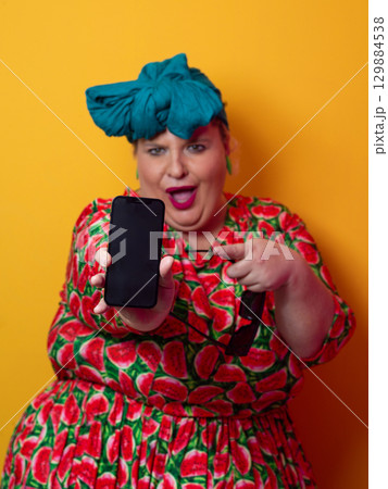 Plus size woman pointing at smartphone with excitement 129884538