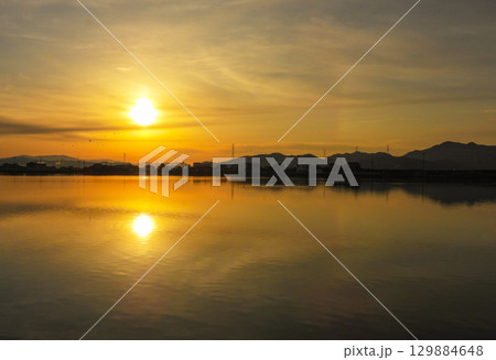 冬の湖面に写る朝日 129884648