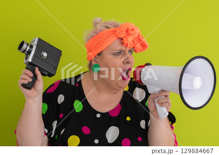 Woman shouting into megaphone and holding vintage camera Woman shouting into megaphone and holding vintage camera 129884667