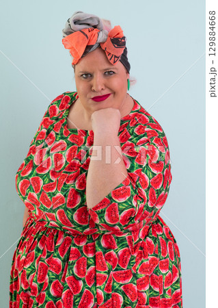 Unimpressed woman in watermelon dress posing with hands on hips Unimpressed woman in watermelon dress posing with hands on hips 129884668