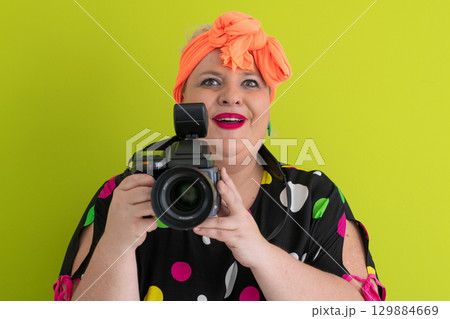Colorful woman holding professional DSLR camera in studio 129884669