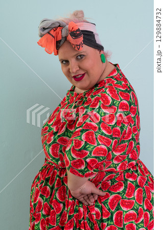 Unimpressed woman in watermelon dress posing with hands on hips 129884732