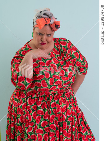 Unimpressed woman in watermelon dress posing with hands on hips Unimpressed woman in watermelon dress posing with hands on hips 129884739
