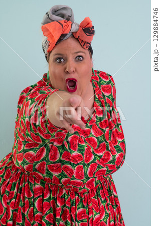 Unimpressed woman in watermelon dress posing with hands on hips Unimpressed woman in watermelon dress posing with hands on hips 129884746