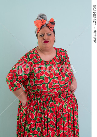 Unimpressed woman in watermelon dress posing with hands on hips 129884759