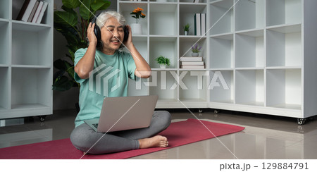 Senior Woman Enjoying Music with Headphones and Laptop in a Modern Home Setting Promoting Wellness and Relaxation Senior Woman Enjoying Music with Headphones and Laptop in a Modern Home Setting Promoting Wellness and Relaxation 129884791