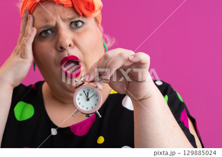 Playful woman in colorful outfit pointing with excited expression 129885024