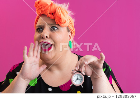 Playful woman in colorful outfit pointing with excited expression Playful woman in colorful outfit pointing with excited expression 129885067