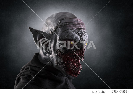 Portrait of a monster with sharp fangs over dark foggy background. Portrait of a monster with sharp fangs over dark foggy background. 129885092