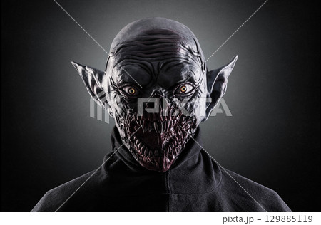 Portrait of a monster with sharp fangs over dark foggy background. 129885119