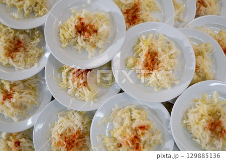 Overhead view of many plates filled with cabbage salad garnished with paprika, catering and food service concept Overhead view of many plates filled with cabbage salad garnished with paprika, catering and food service concept 129885136