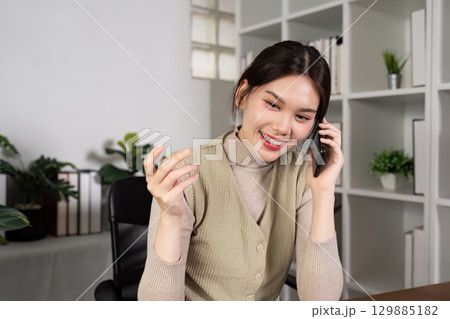 Confident Businesswoman in Modern Office Holding Smartphone and Coffee Cup, Surrounded by Greenery and Contemporary Workspace Confident Businesswoman in Modern Office Holding Smartphone and Coffee Cup, Surrounded by Greenery and Contemporary Workspace 129885182