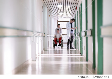 Young Male Patient in Wheelchair Assisted by Female Medical Professional Young Male Patient in Wheelchair Assisted by Female Medical Professional 129885364