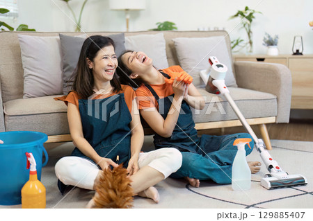 Mother and Daughter Enjoying a Fun Cleaning Day at Home with Cleaning Supplies and Vacuum in Cozy Living Room Mother and Daughter Enjoying a Fun Cleaning Day at Home with Cleaning Supplies and Vacuum in Cozy Living Room 129885407
