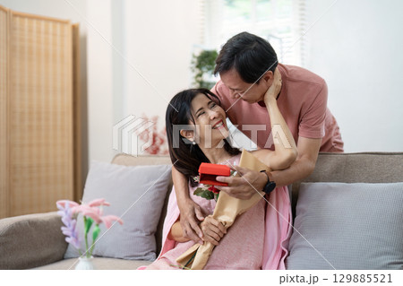 Joyful Senior Couple Celebrating Valentine's Day with Flowers and Gifts in a Cozy Home Setting 129885521
