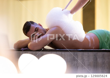 Foam Massage Session.Hamam attendant applying foam massage on patient back with circular motions. Foam Massage Session.Hamam attendant applying foam massage on patient back with circular motions. 129885624