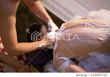 Back Massage with Foam.Therapist applying soap foam with hands on patient back during traditional bath ritual. 129885726