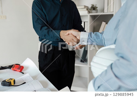 Professional Engineers Collaborating on Architectural Project with Blueprints and Tools in Modern Office Setting 129885945