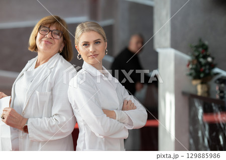 Healthcare workers smiling back to back in clinic Healthcare workers smiling back to back in clinic 129885986