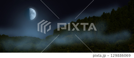 Moon at night, starless sky. Fog over mountain woodland 129886069