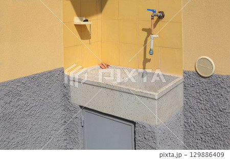 Water tap with stone sink on terrace in courtyard of house in summer, Italy. Buildings and traditional houses of Liguria. 129886409