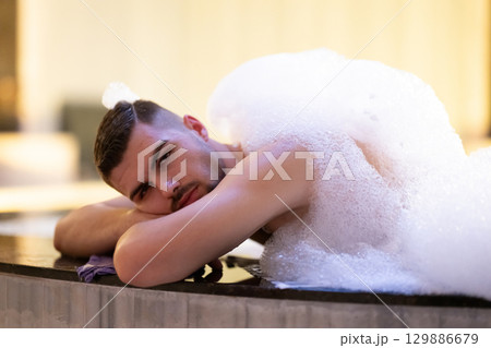 Man Relaxing in Foam.Relaxed man lying in Turkish bath covered in white foam during cleansing ritual. 129886679