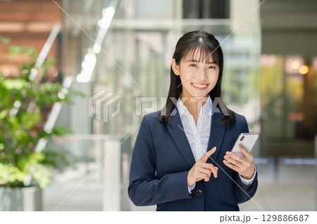 スマートフォンを操作する若いビジネスウーマン スマートフォンを操作する若いビジネスウーマン 129886687