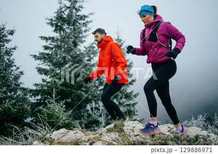 Trail running couple man and woman running on a mountain path 129886971