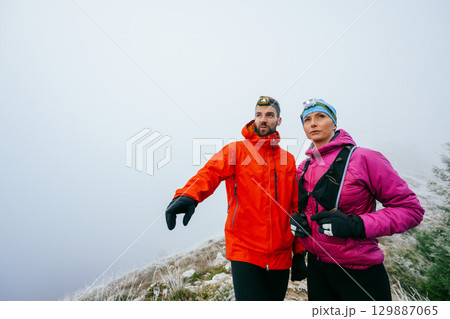 Man Pointing While Hiking with Woman.Man pointing while hiking with a female partner on a foggy mountain slope. 129887065