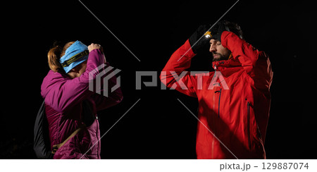 Nighttime First Aid in the Wilderness.A woman provides headlamp-assisted first aid to a man outdoors in the dark, showcasing emergency preparedness in extreme conditions. Nighttime First Aid in the Wilderness.A woman provides headlamp-assisted first aid to a man outdoors in the dark, showcasing emergency preparedness in extreme conditions. 129887074