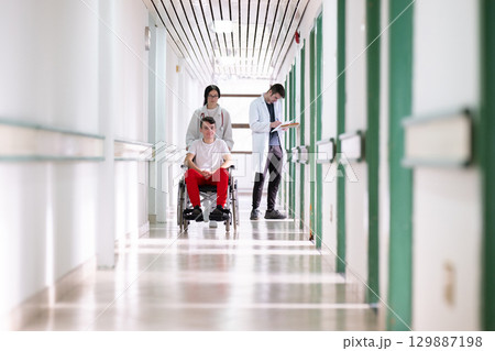 Young Male Patient in Wheelchair Assisted by Female Medical Professional 129887198