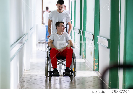 Young Male Patient in Wheelchair Assisted by Female Medical Professional Young Male Patient in Wheelchair Assisted by Female Medical Professional 129887204
